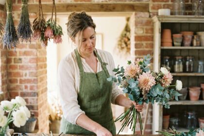 Fleuriste femme arrangeant un bouquet de fleurs fraîches dans une boutique artisanale au décor rustique